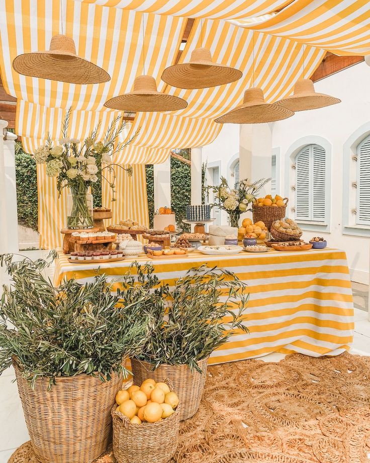 A vibrant citrus-themed wedding dessert table with yellow and white striped canopy and eco-friendly rustic décor, for a Mediterranean-inspired celebration.